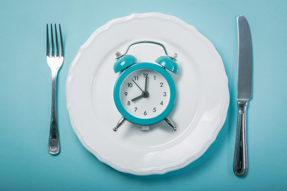 Intermittent fastin concept – empty plate on blue background